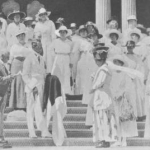 C.P. Iaukea holding Queen Liliuokalani's Red Cross Flag on steps of Iolani Palace while Gov. Pinkham speaks